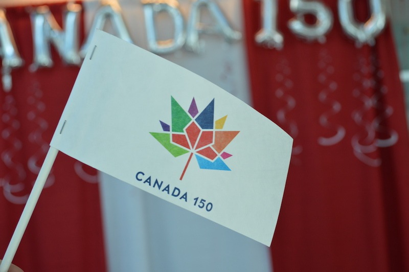 A photo of a Canada 150 flag, with a Canada 150 backdrop in the background.